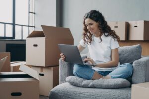 Jeune femme assise avec sopn ordinateur au milieu de cartons