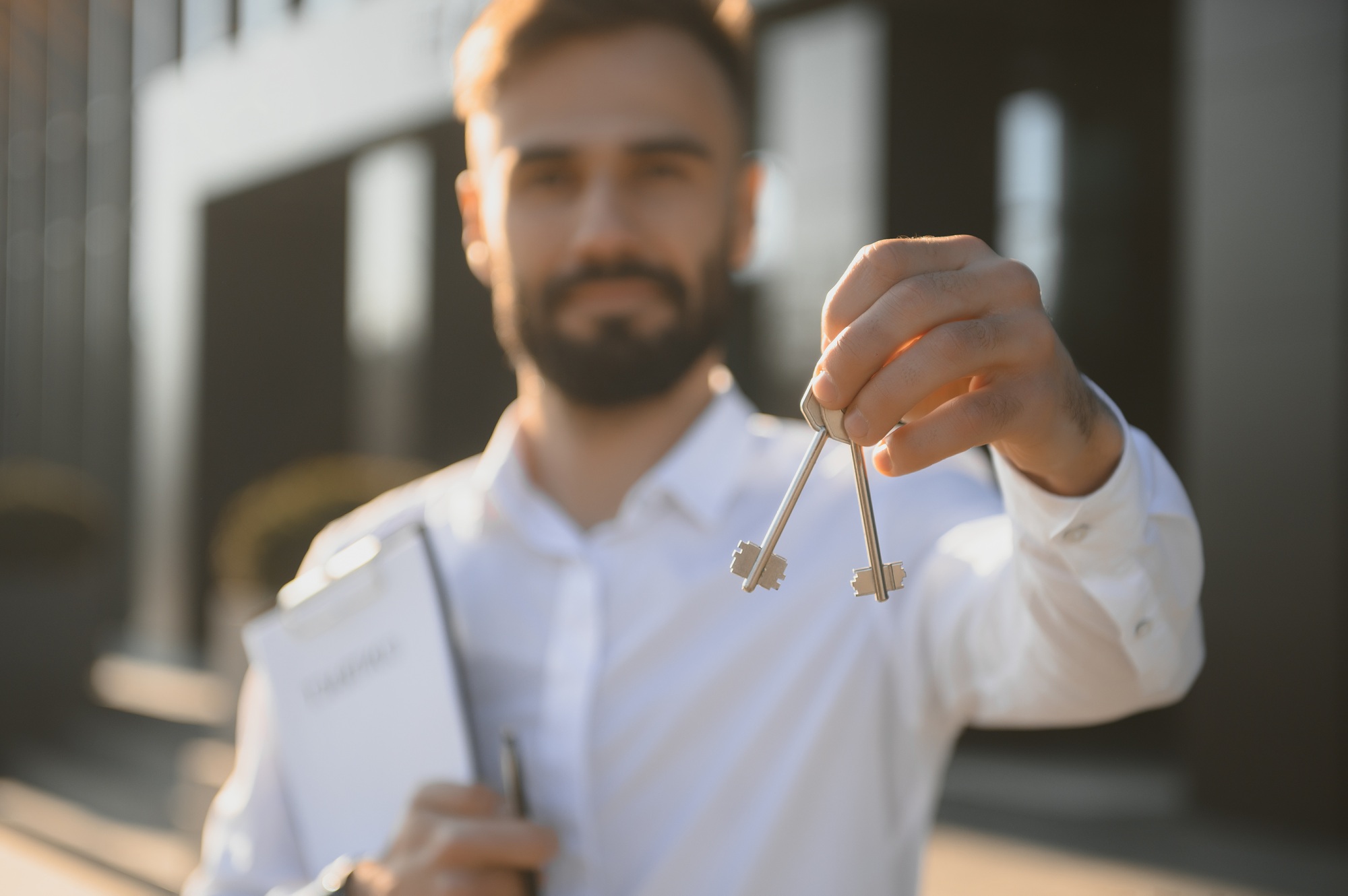 Real estate agent holding key on blurred background, closeup