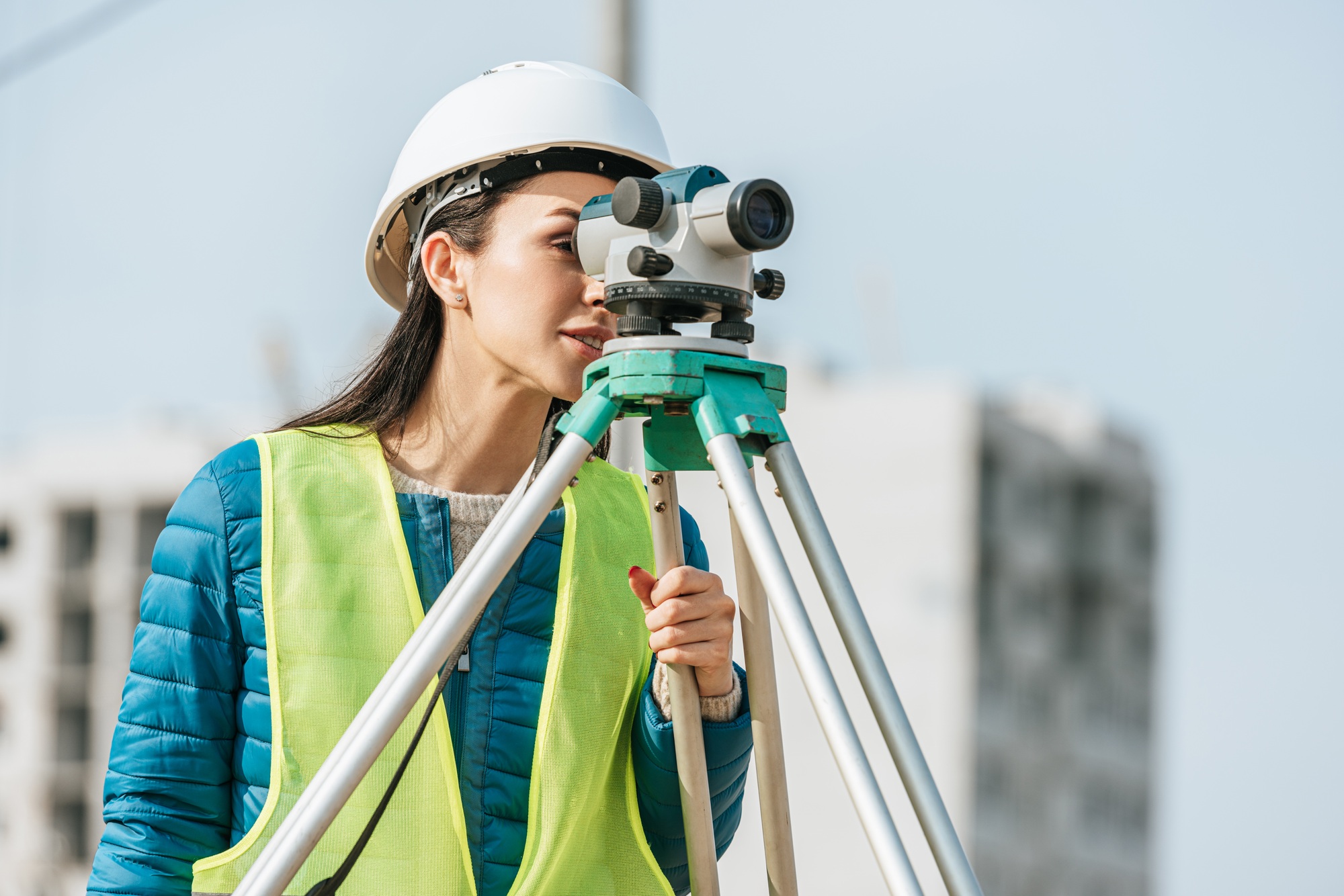 Surveyor in hardhat and high visibility jacket looking in digital level